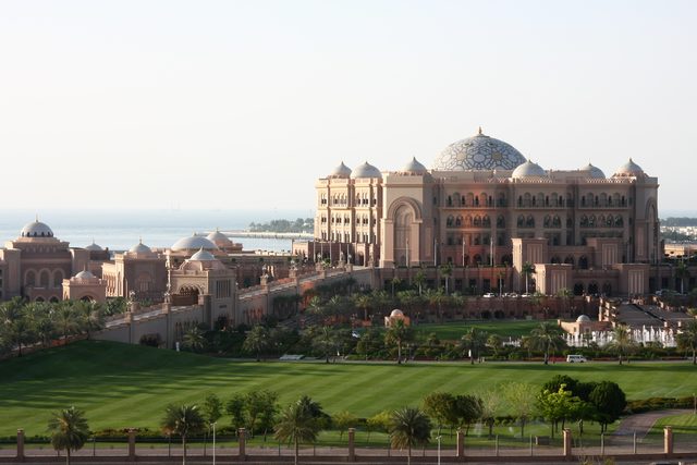 Вид на отель Emirates Palace в Абу-Даби с зеленым газоном и морем на фоне