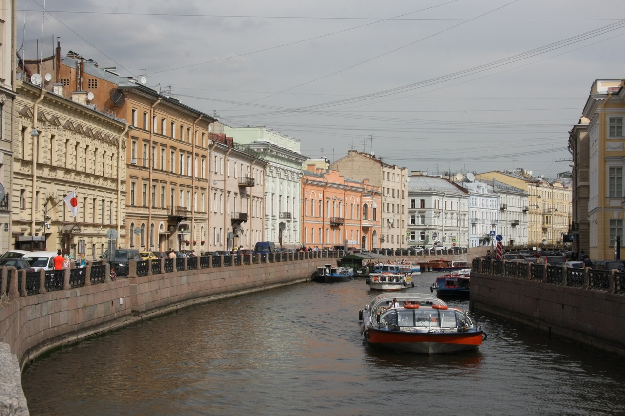 Туристические теплоходы плывут по реке Мойке в Санкт-Петербурге на фоне исторической застройки набережной.