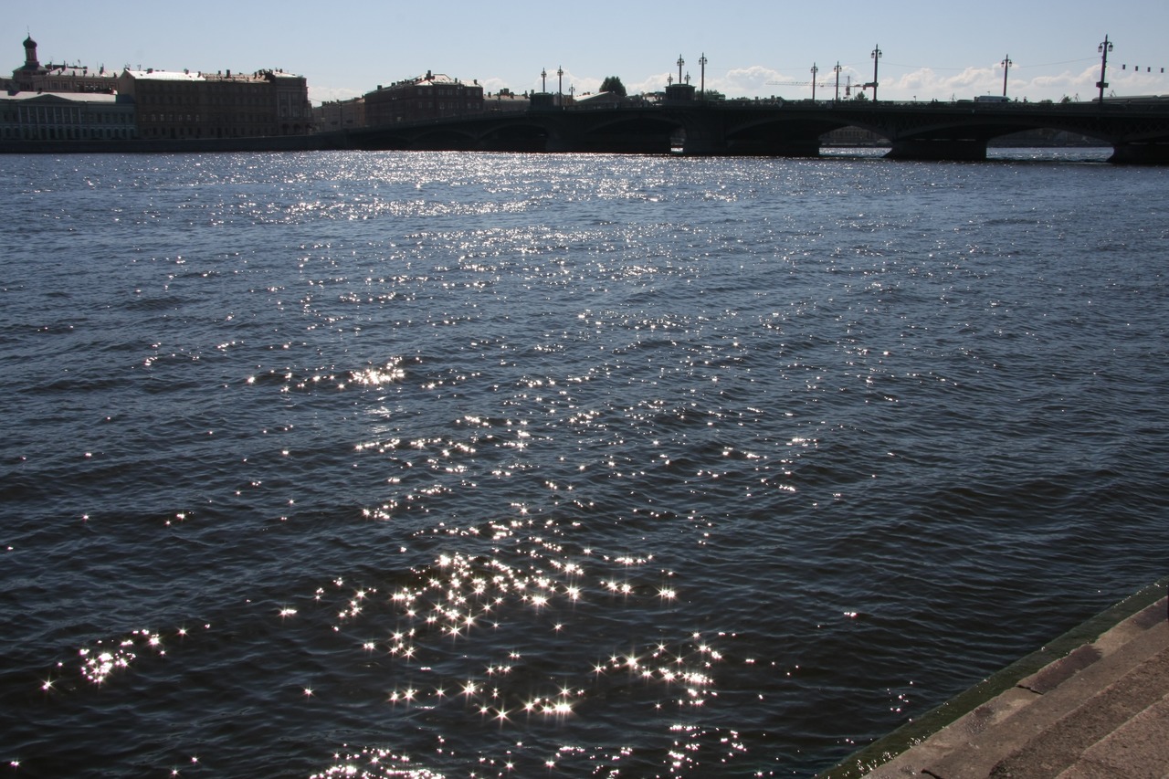 Река Нева и мост в Санкт-Петербурге с солнечными бликами на воде