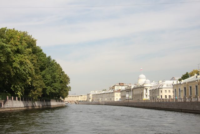 Вид на реку Фонтанку в Санкт-Петербурге с зелеными деревьями и историческими зданиями на фоне.