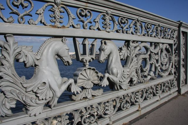 Деталь чугунного ограждения Благовещенского моста с фигурами коней и трезубца на фоне реки