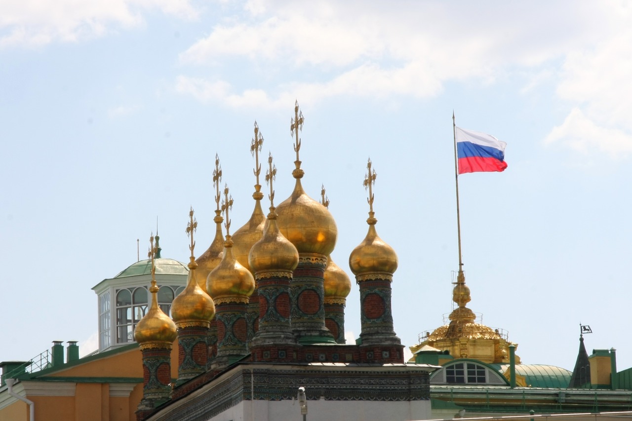 Вид на золотые купола Верхоспасского собора и российский флаг на фоне неба