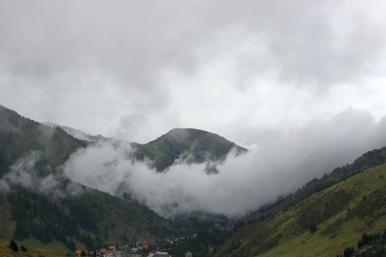 Горный пейзаж с облаками и лесом в предгорьях Тянь-Шаня
